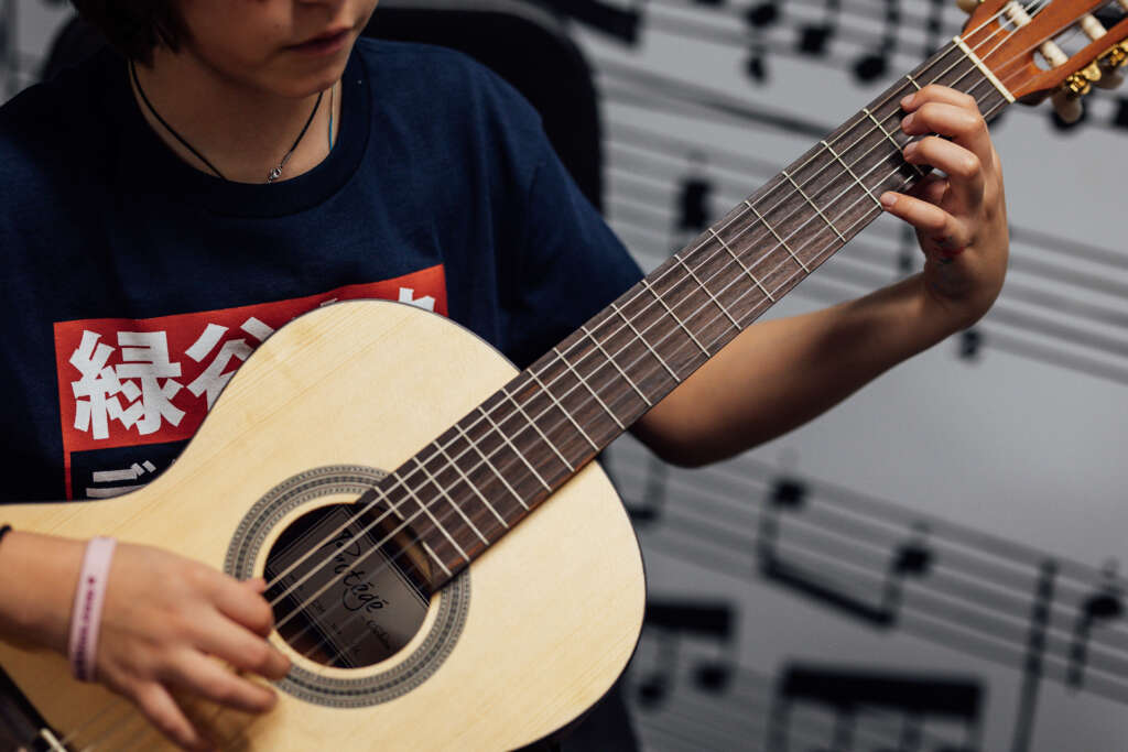 Student plays guitar during a music lesson
