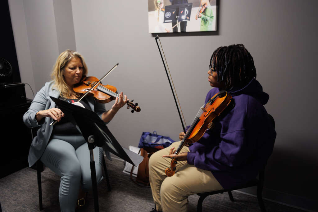 A violin student receives instruction from a teacher
